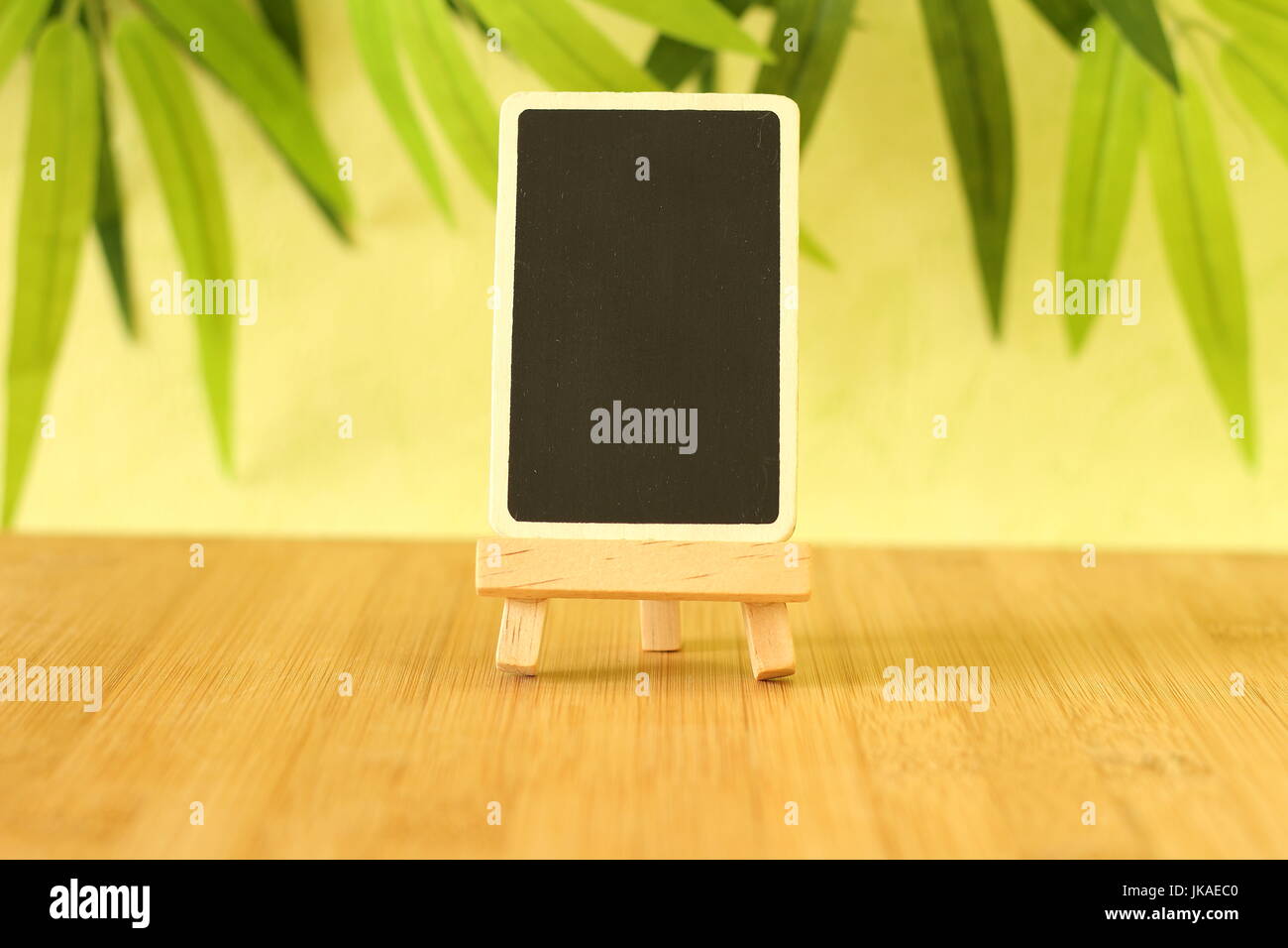 Petite ardoise vide de hauteur d'écrire un message qui est posé sur un chevalet tout sur un plancher en bois et le feuillage vert contexte Banque D'Images