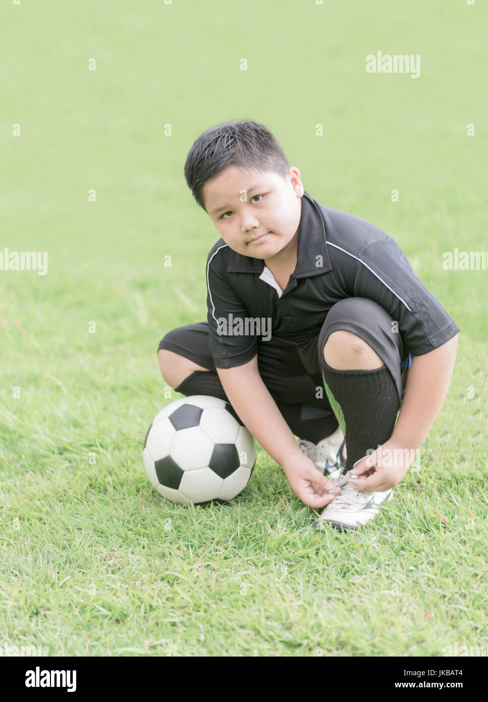 Garçon obèse étant prête pour le match de football jeu de lier ses chaussures, concept sain Banque D'Images