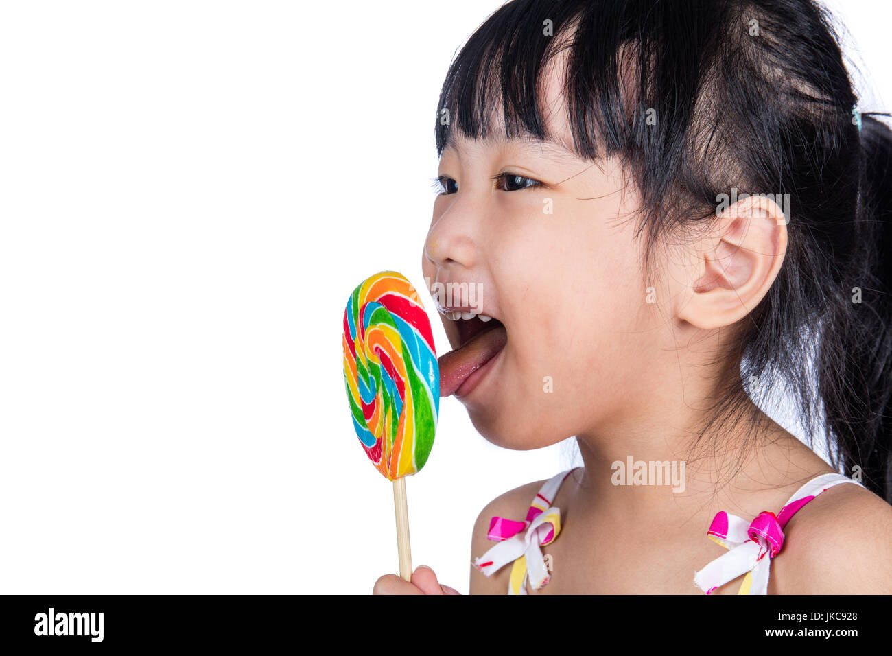 Peu asiatique Chinese girl eating lollipop isolé en fond blanc Banque D'Images