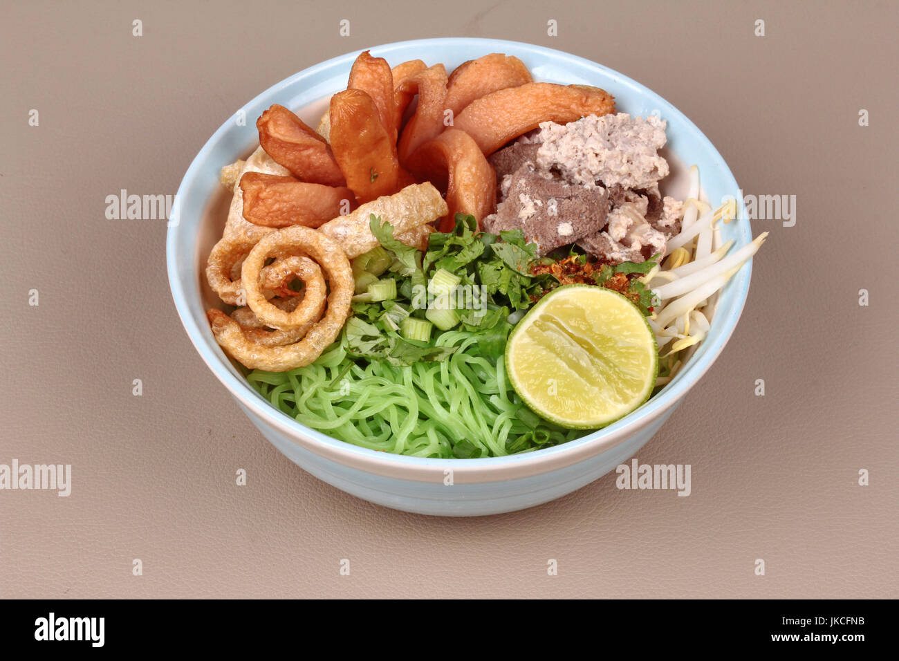 Nouilles vertes avec tom yam en tête de porc émincé de foie de poulet, saucisses,2015,le citron,germes de haricots, piment, coriandre et couenne de porc. Banque D'Images