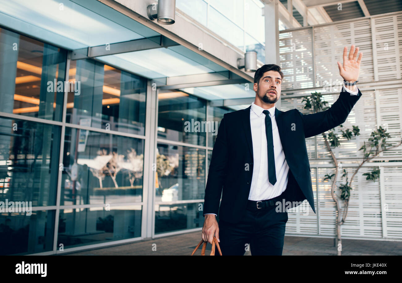 Handsome businessman calling taxi en arrivant de voyage d'affaires. Young caucasian business executive appelant cab au terminal de l'aéroport. Banque D'Images