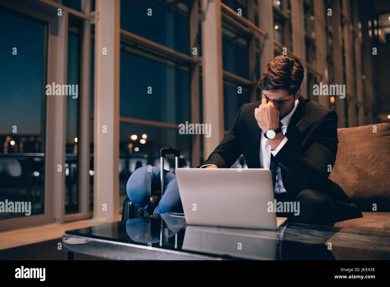 Fatigué d'affaires en attente de vol retardé in airport lounge. Jeune homme assis dans la salle d'attente avec coffre sentiment épuisé. Banque D'Images