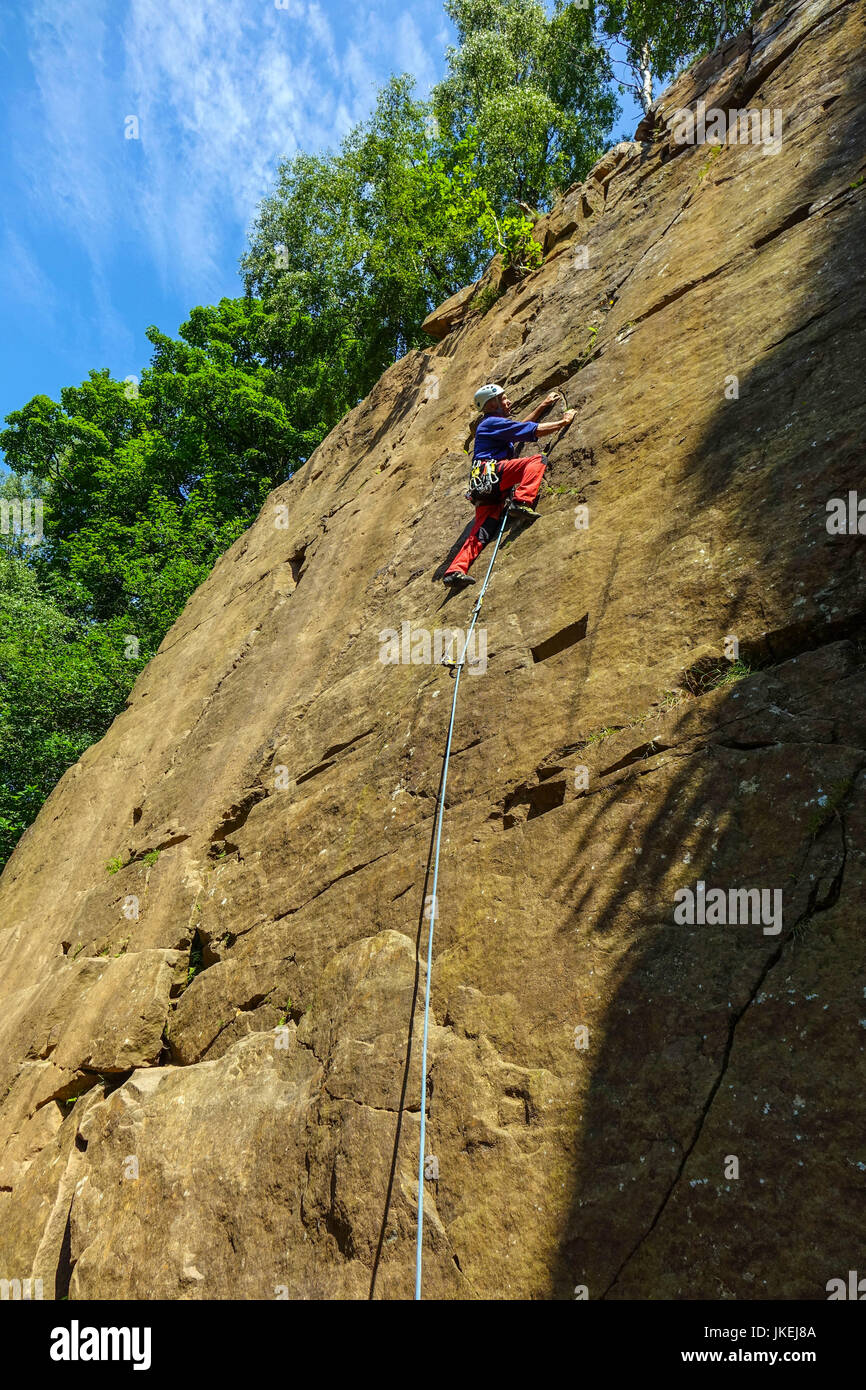 Male rock climber climbing à Yarncliffe Quarry, Derbyshire Banque D'Images