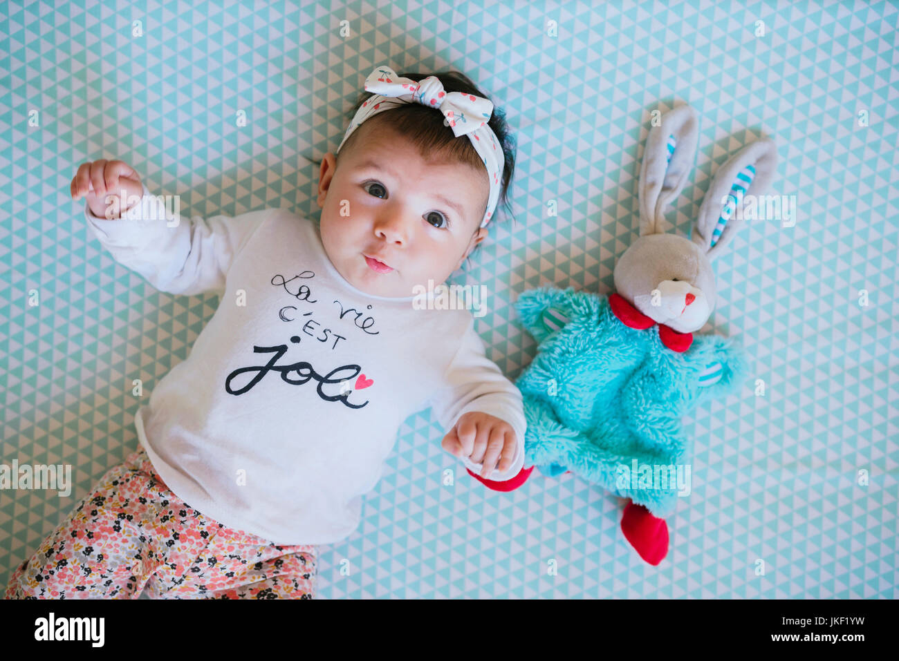 Baby Girl lying on lit à côté de toy bunny Banque D'Images