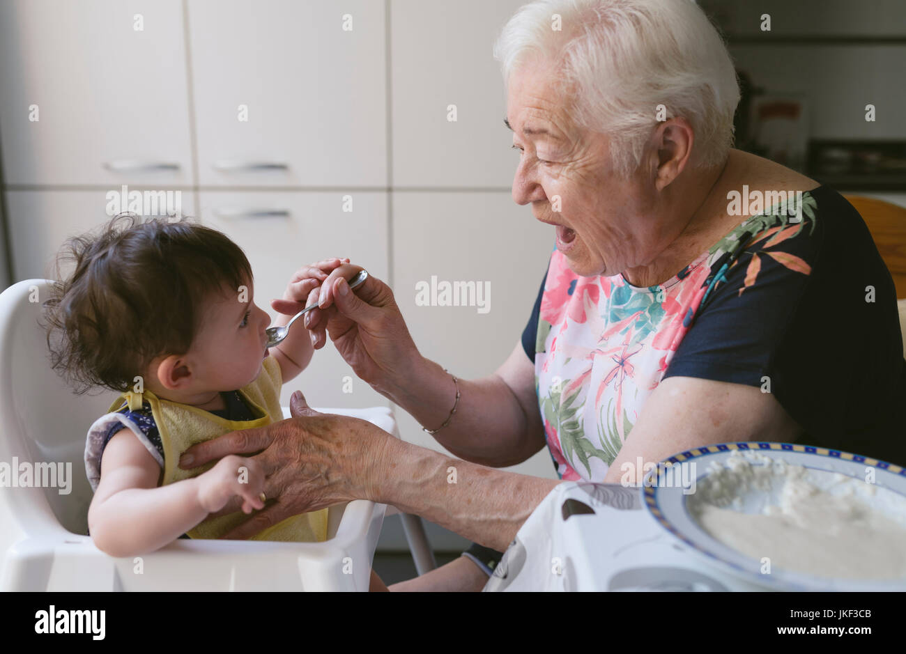 Grand-mère nourrir bébé fille dans la cuisine Banque D'Images