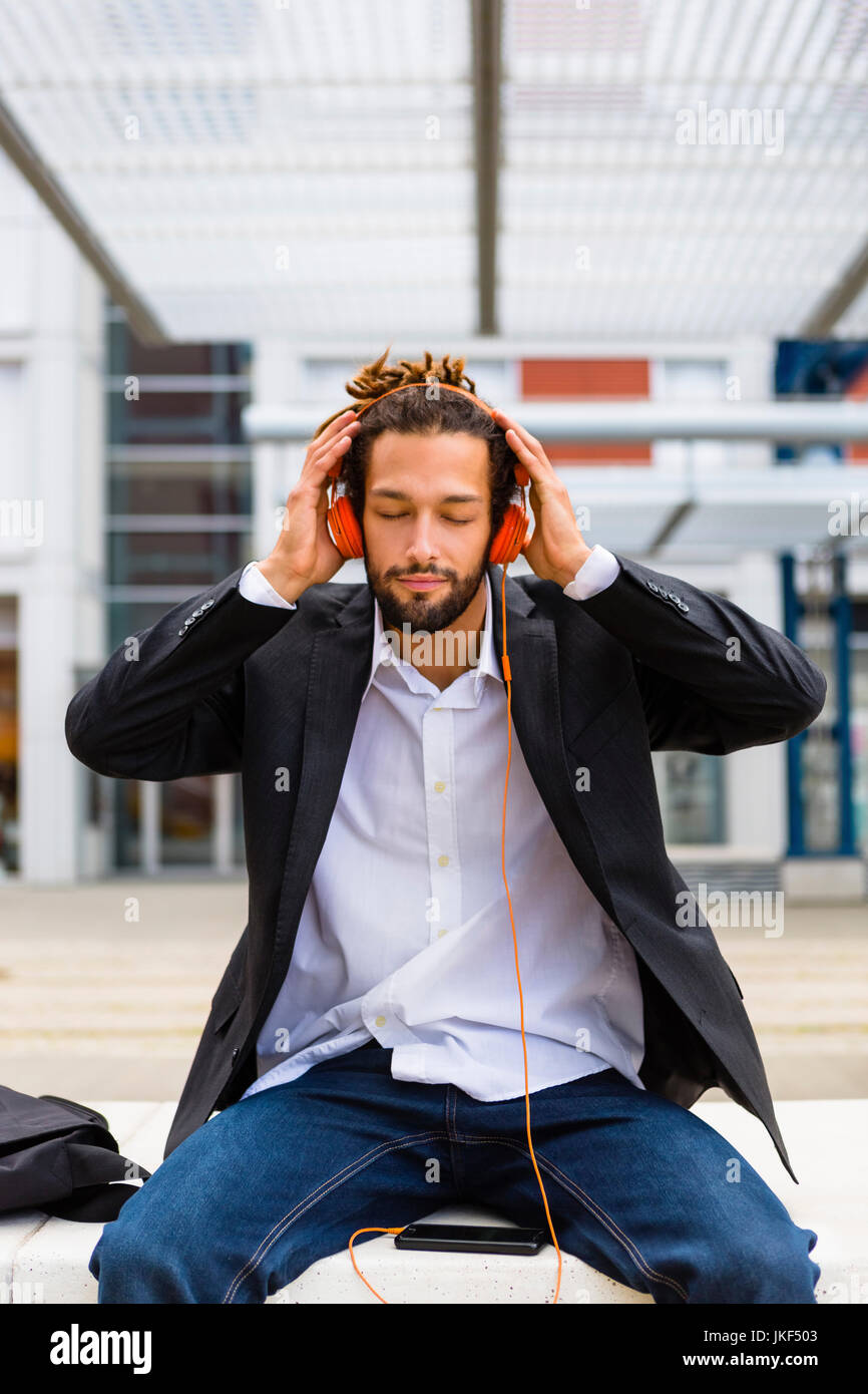 Italie, Florence, jeune homme avec des dreadlocks écouter de la musique dans la ville Banque D'Images
