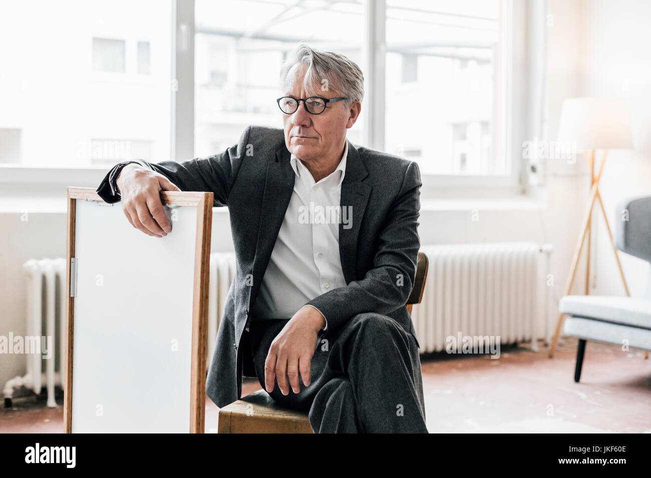 Senior businessman sitting on chair avec cadre Banque D'Images