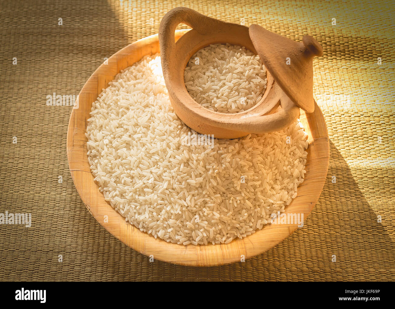 Petit tas de riz long grain blanc sur une surface en bois avec éclairage naturel montrant les ombres et le riz Banque D'Images