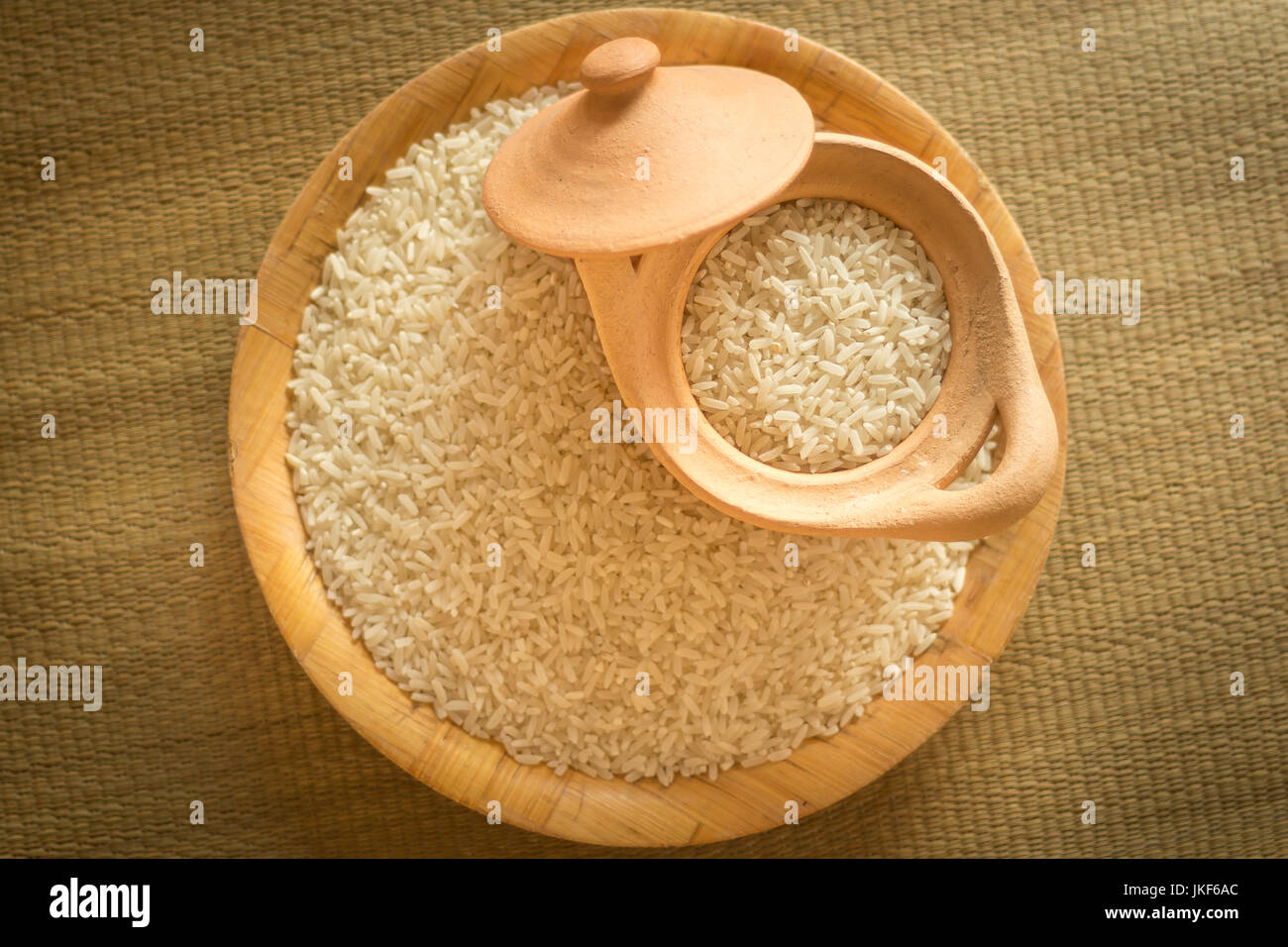 Petit tas de riz long grain blanc sur une surface en bois avec éclairage naturel montrant les ombres et le riz Banque D'Images