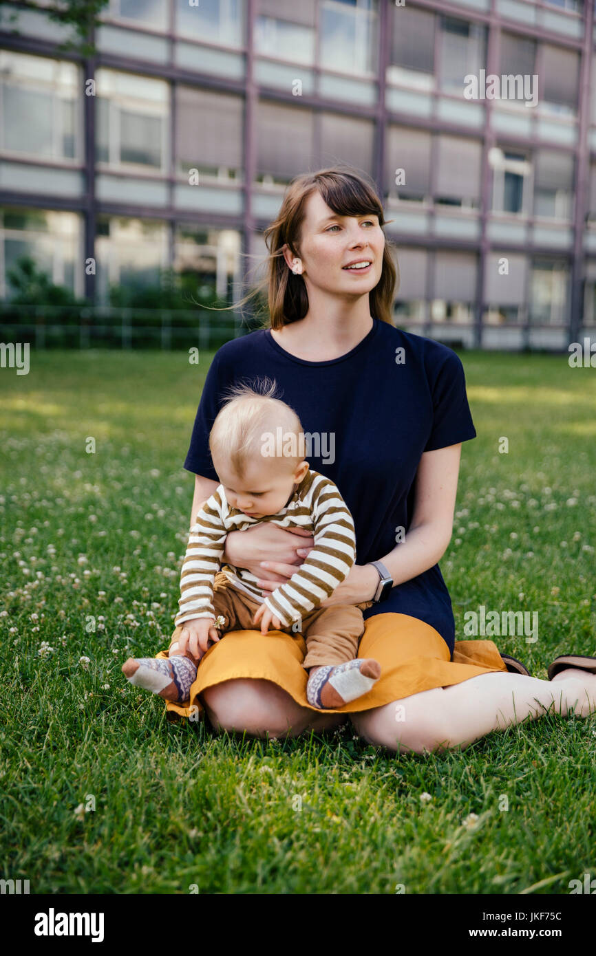 Mère assise avec son bébé garçon sur un pré Banque D'Images