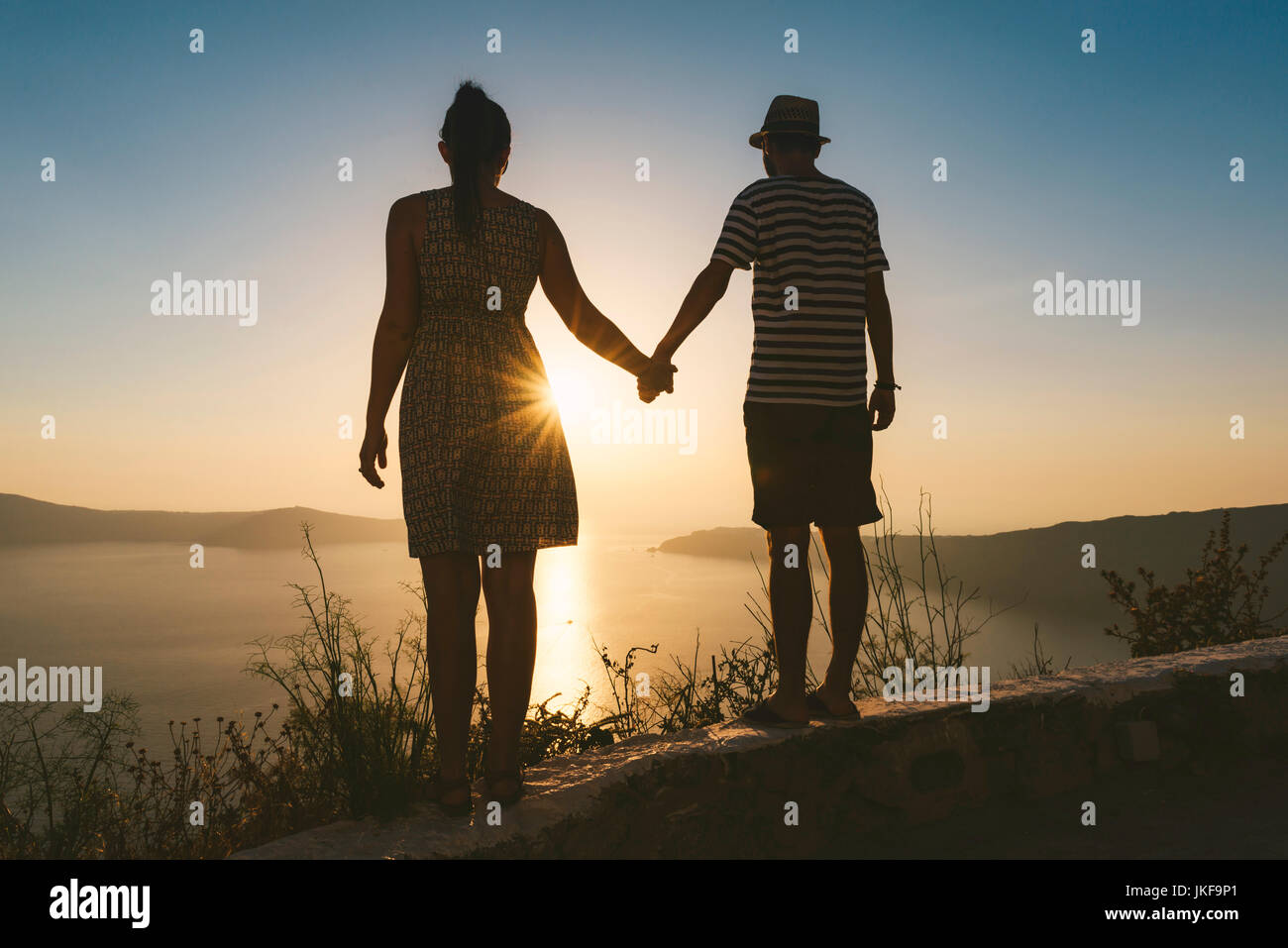 Fira, Santorini, Grèce. Couple holding hands and enjoying coucher de soleil sur la caldeira de Santorin Banque D'Images