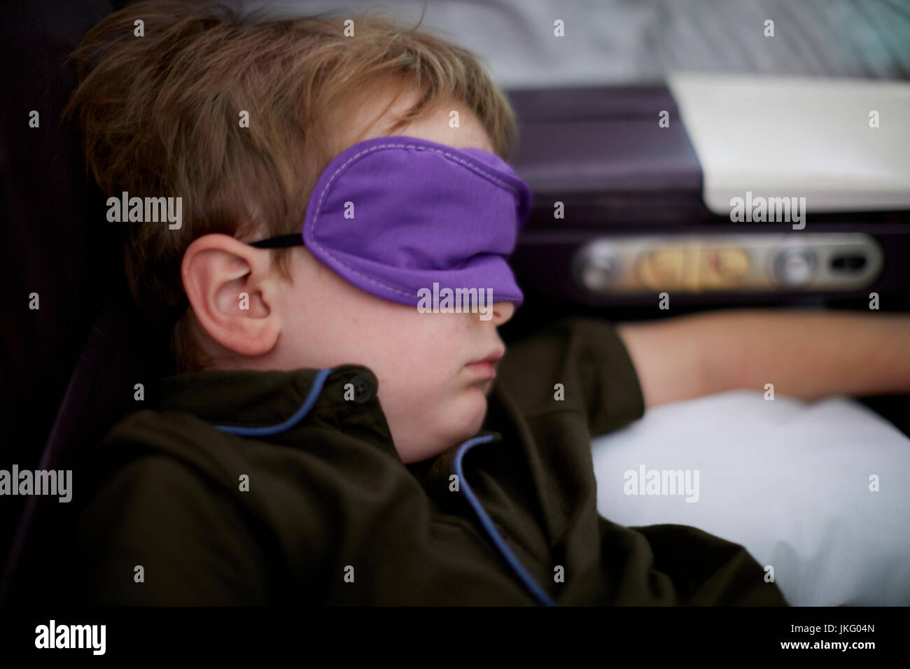 New York City, United States, l'aéroport JFK, un petit garçon enfant dormir sur un vol long courrier en utilisant le masque pour couvrir ses yeux Banque D'Images