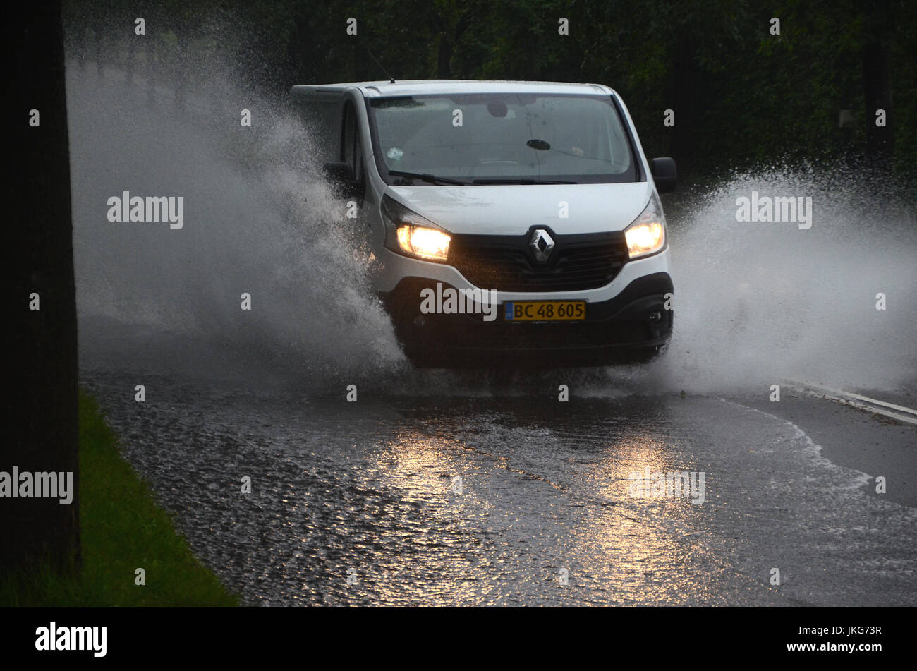 Sonderborg, Danemark - Juillet 23, 2017 : l'eau creux éclaboussures Van sur une route partiellement inondé pendant une forte pluie. Banque D'Images