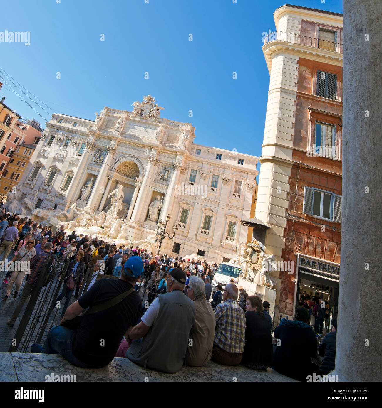 Vue sur place de gens assis au bord de la fontaine de Trevi à Rome. Banque D'Images