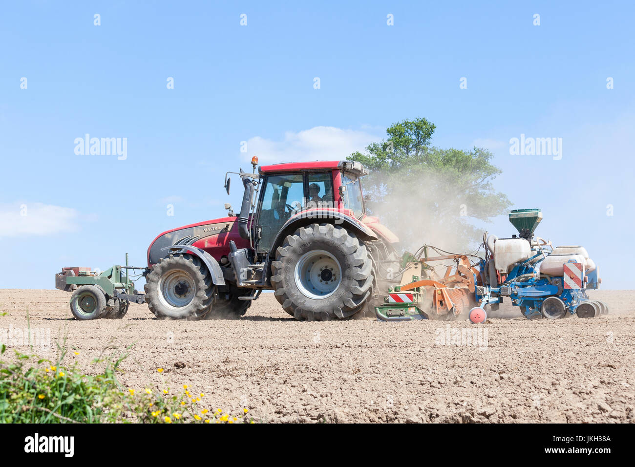 Le forage et l'agriculteur la plantation La récolte de printemps de maïs dans un champ labouré à l'aide d'un tracteur Valtra et Monosem NG plus 4 cinq rangs pneumatique Banque D'Images