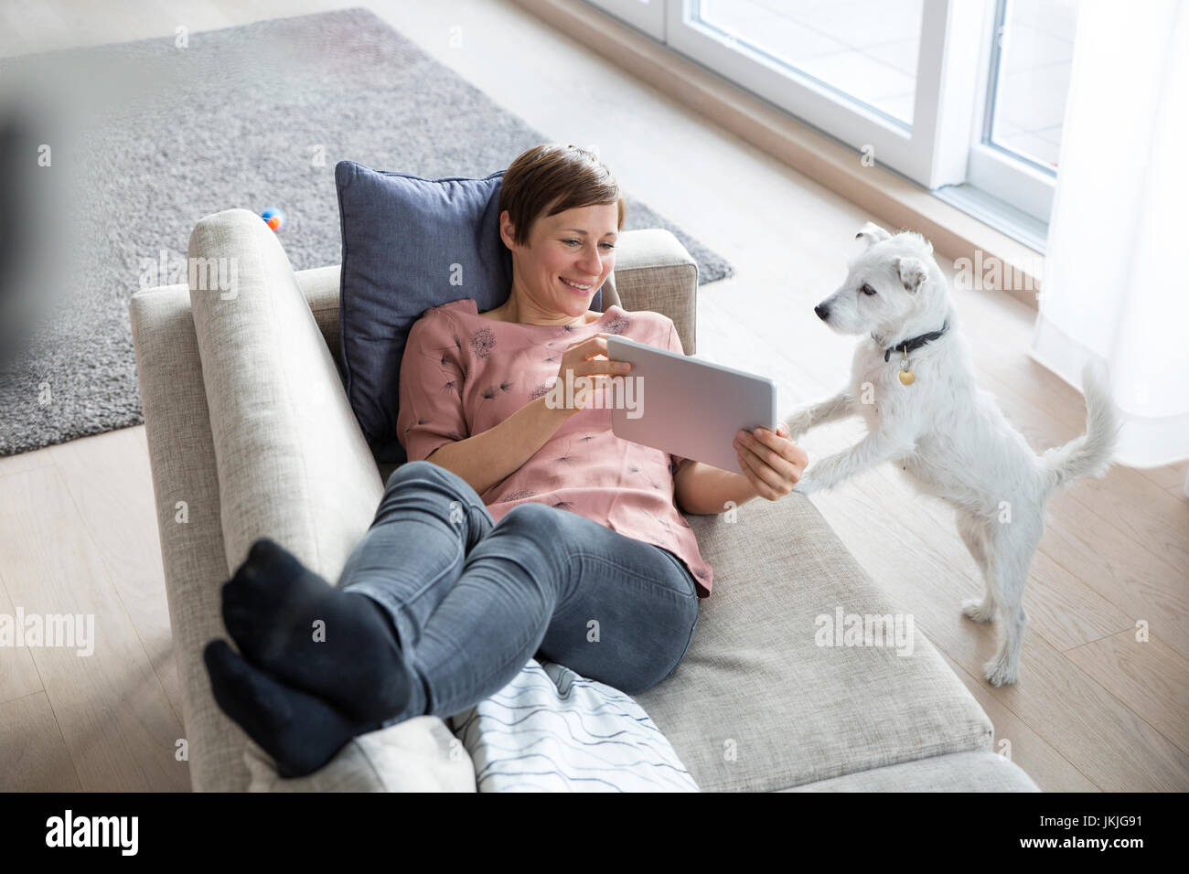 Portrait of smiling woman relaxing with tablet sur le canapé Banque D'Images