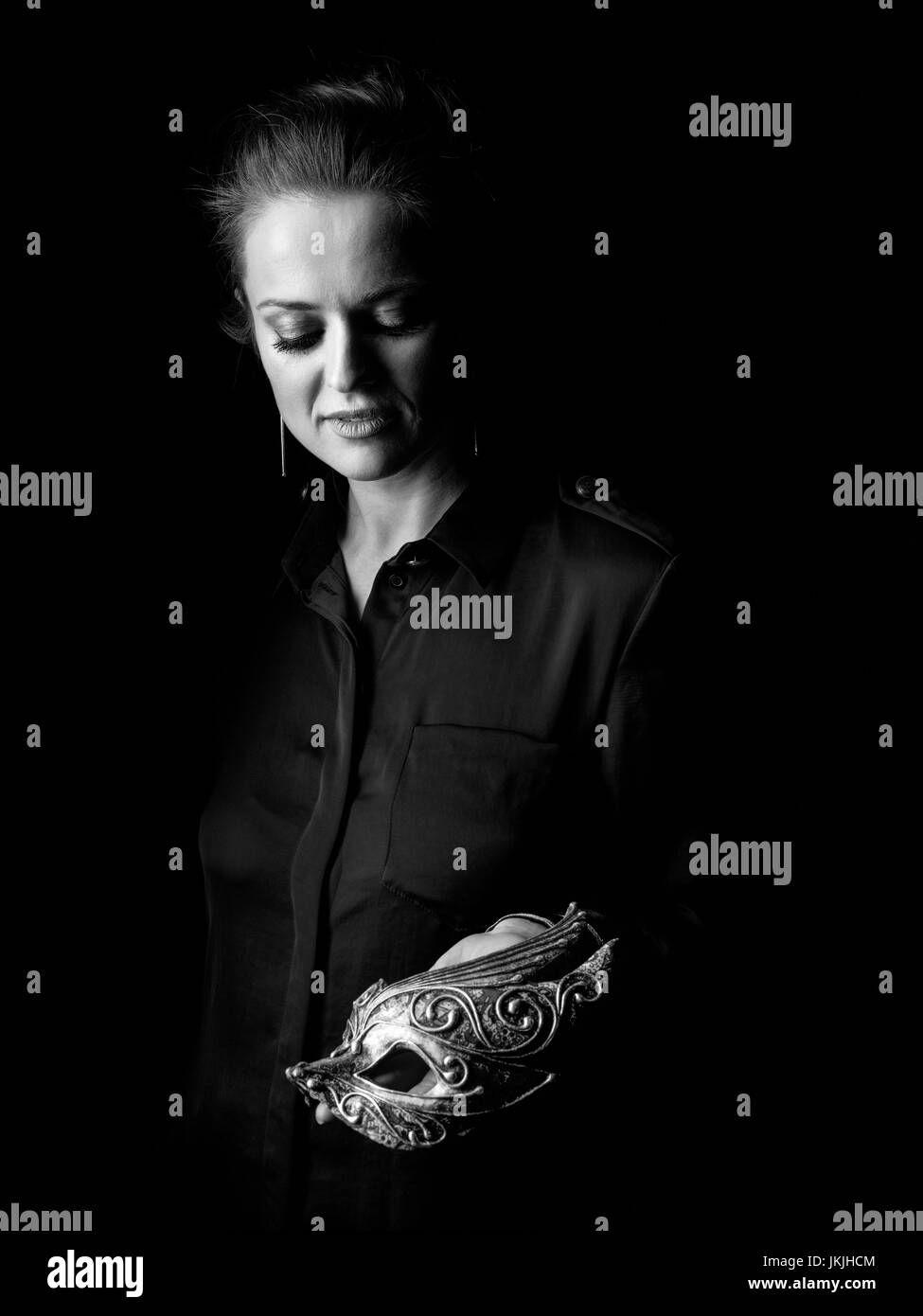 Сoming dans la lumière. La femme de la robe sombre isolé sur montrant noir masque de Venise Banque D'Images