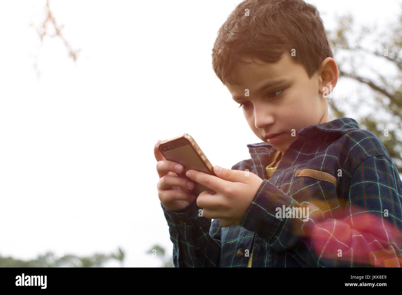 Un jeune garçon à l'extérieur jouer Pokemon rendez sur un téléphone intelligent. Banque D'Images