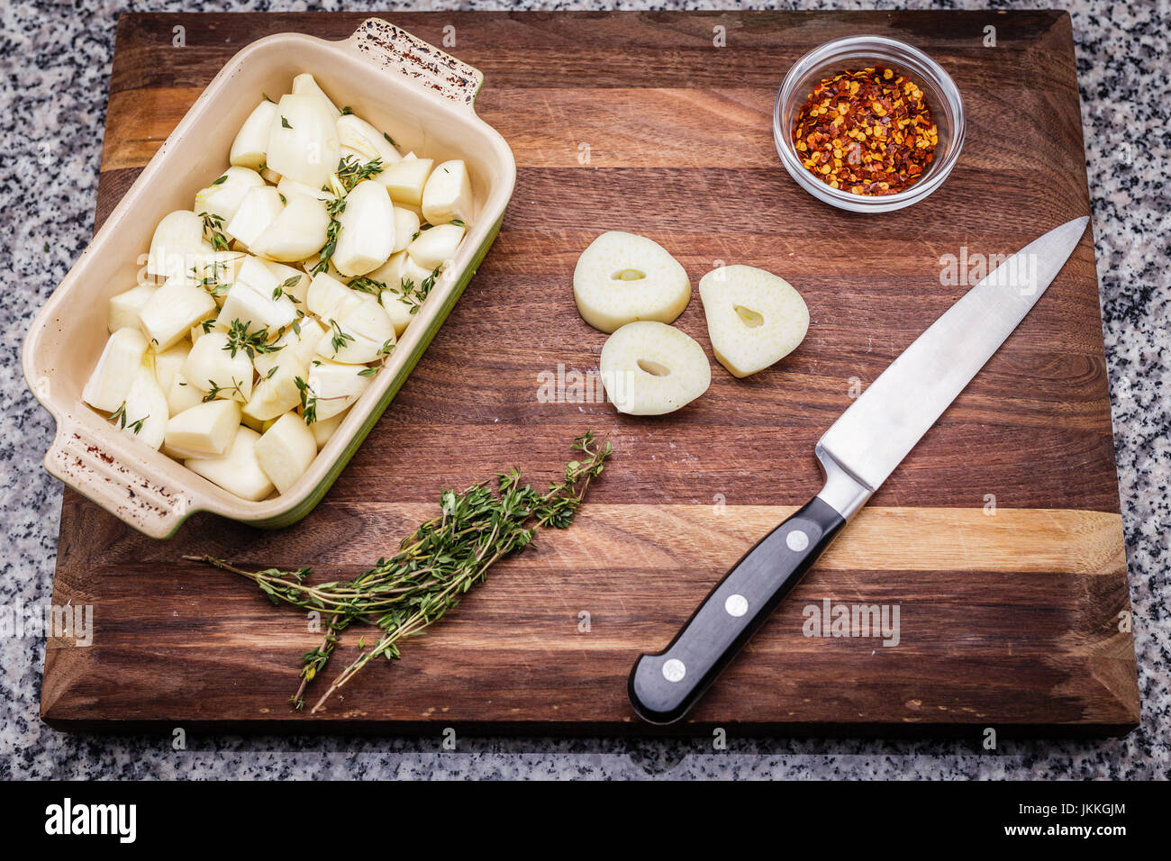 Ingrédients pour la préparation de l'ail rôti au thym frais, comprend et piment rouge broyé. L'ail haché dans un plat de cuisson en céramique. Couteau et roasti Banque D'Images