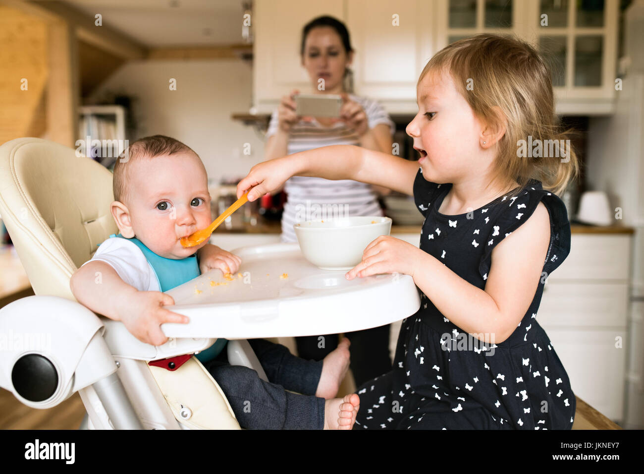 Adorable bébé fille à nourrir son petit frère. Banque D'Images