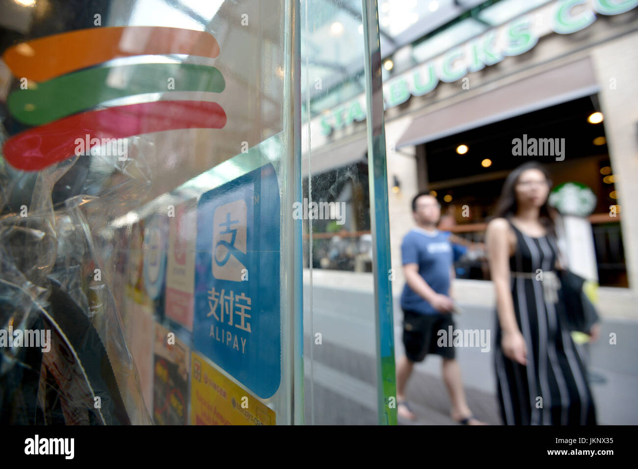 (170724) -- PARIS, le 24 juillet 2017 (Xinhua) -- Les piétons devant une strore avec le logo de Alipay sur la porte en verre à Kuala Lumpur, Malaisie, le 24 juillet 2017. La deuxième plus grande banque CIMB mains jointes avec Ant Financial, une filiale du géant de l'e-commerce chinois Alibaba, le lundi pour répondre aux demandes de paiement mobile. (Xinhua/Chong Voon Chung) (srb) Banque D'Images