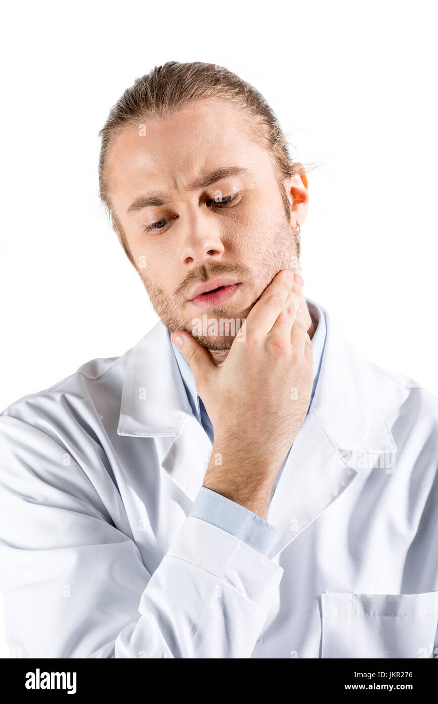 Portrait of pensive young doctor in white coat isolated on white Banque D'Images