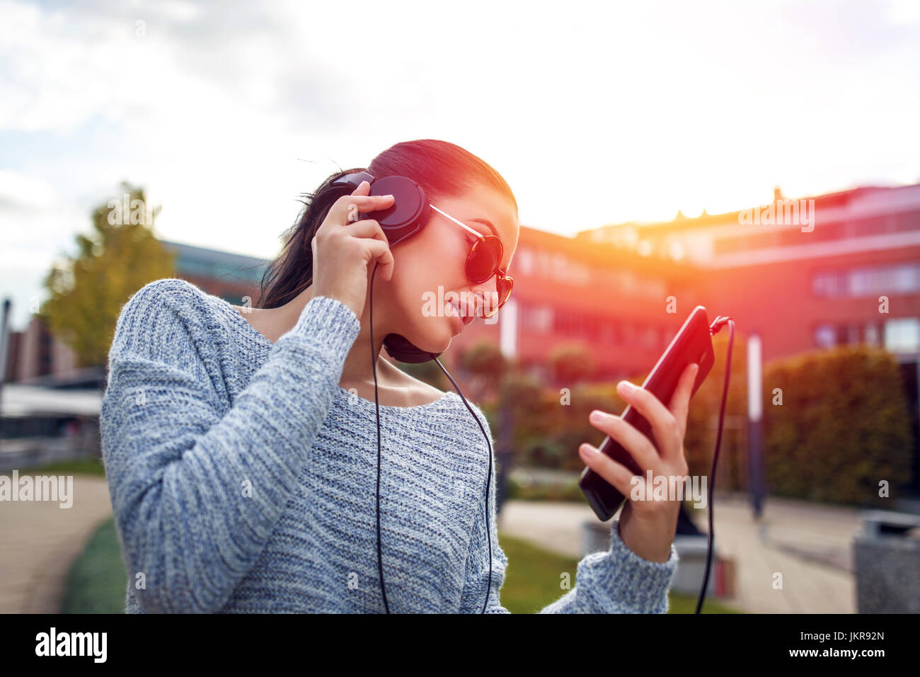 Young woman listening music par comprimé et les écouteurs en ville, au coucher du soleil en plein air Banque D'Images