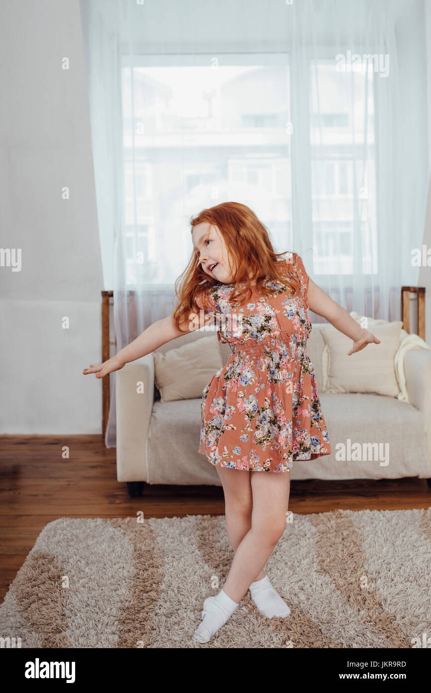 Happy girl with arms outstretched danser sur un tapis à la maison Banque D'Images