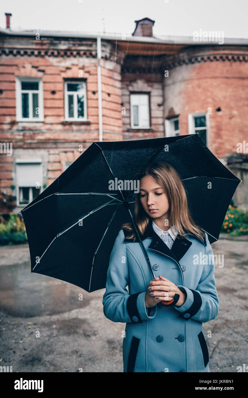 Thoughtful woman holding umbrella debout contre le bâtiment Banque D'Images