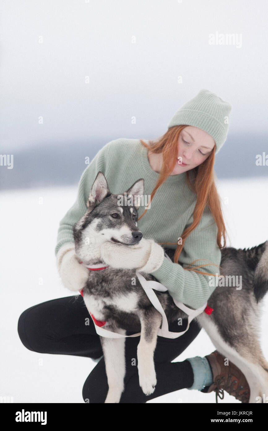 Belle jeune femme caressant Husky Sibérien sur champ neigeux Banque D'Images
