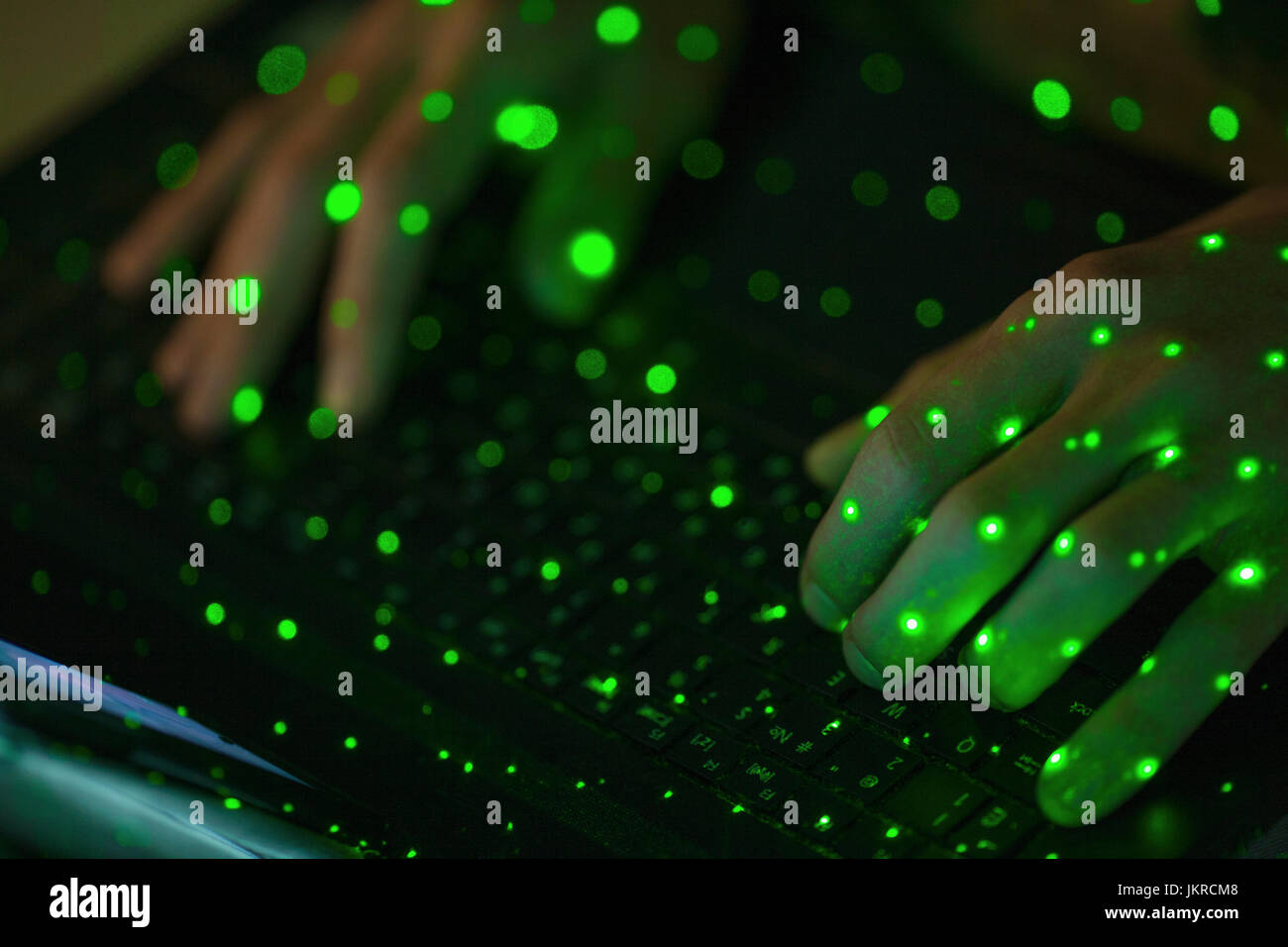Close-up of green lights sur les mains coupées à l'aide du clavier d'ordinateur portable Banque D'Images