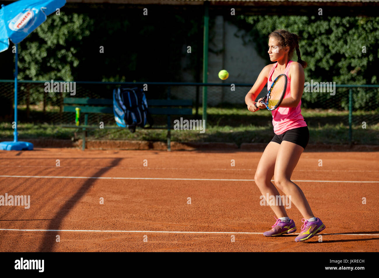 Jeune fille jouant au tennis sur terre battue rouge Banque D'Images