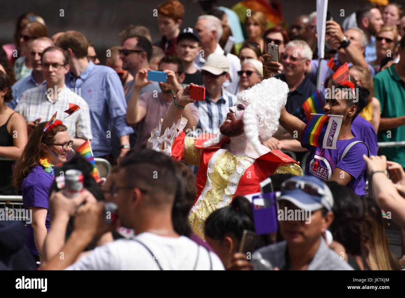 Reveler, vêtus de costumes baroques, avec barbe rouge et perruque blanche prend une photo à la fierté selfies à Londres parade, 2017. Banque D'Images