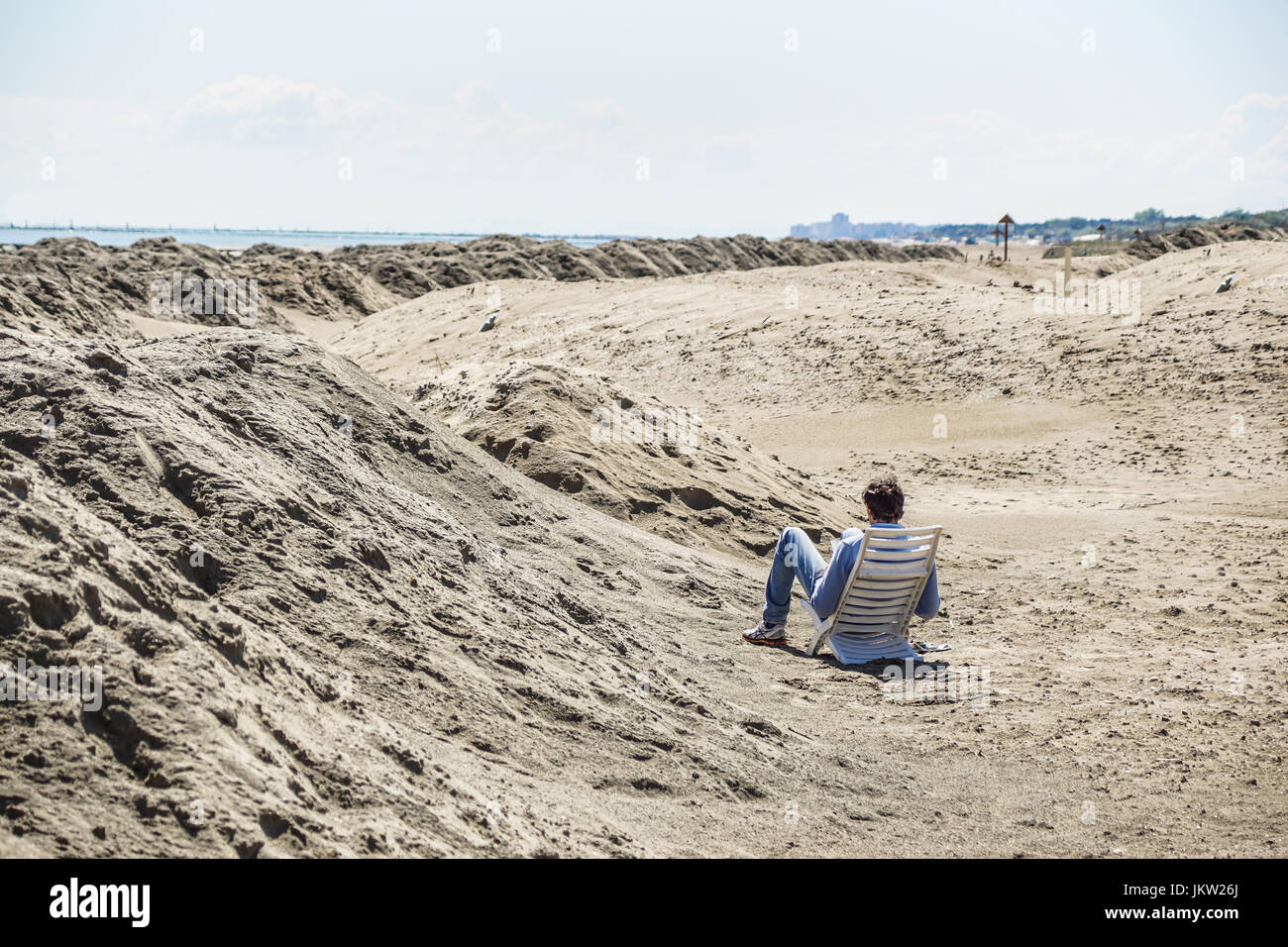 Vue arrière d'un jeune homme lisant un livre sur la plage Banque D'Images