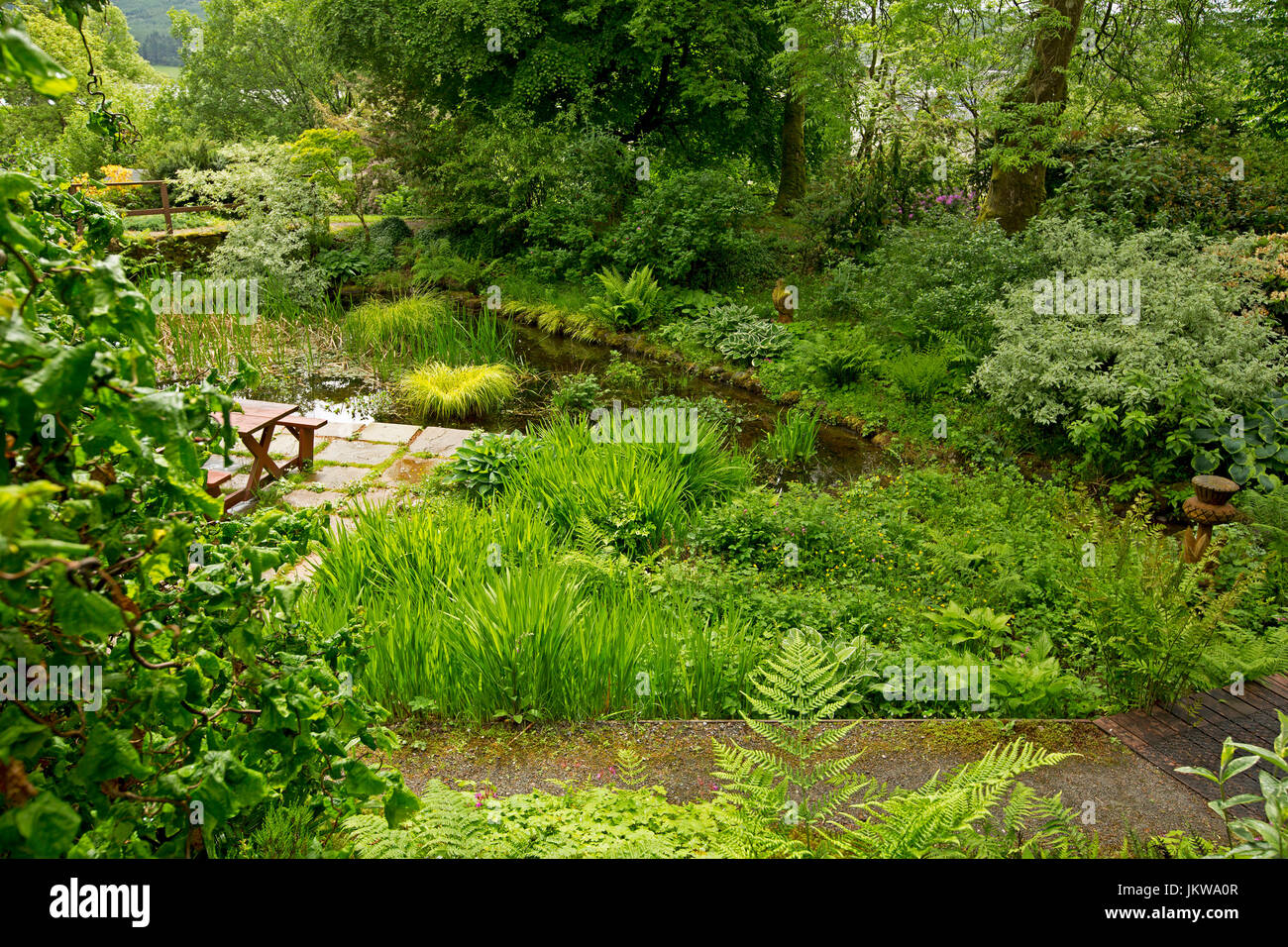 Jardin communautaire spectaculaire avec de l'eau fonction, pavage, table de pique-nique et arbres se reflétant dans l'eau de piscine au calme - en Ecosse Banque D'Images