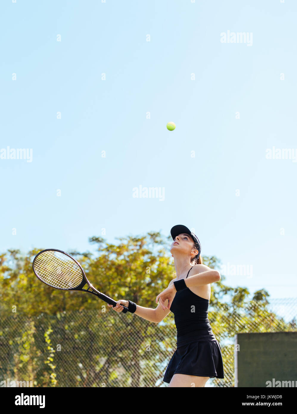 Tennis player sur le point de frapper la balle. Les jeunes de la sportive en jouant au tennis sur le court sur une journée d'été. Banque D'Images