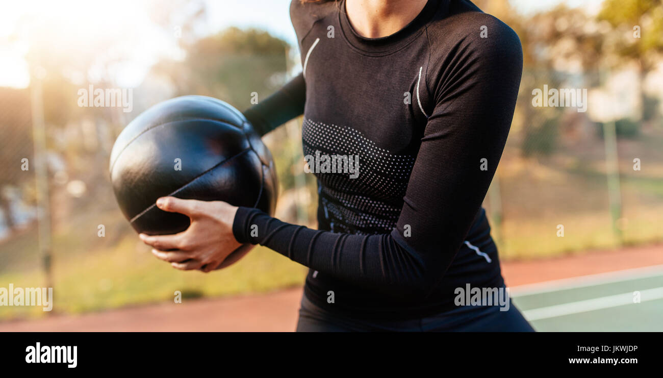 Cropped shot of fit young woman working out avec ballon. Close up de la sportive s'entraîner avec le fitness ball en extérieur sur un court de tennis. Banque D'Images