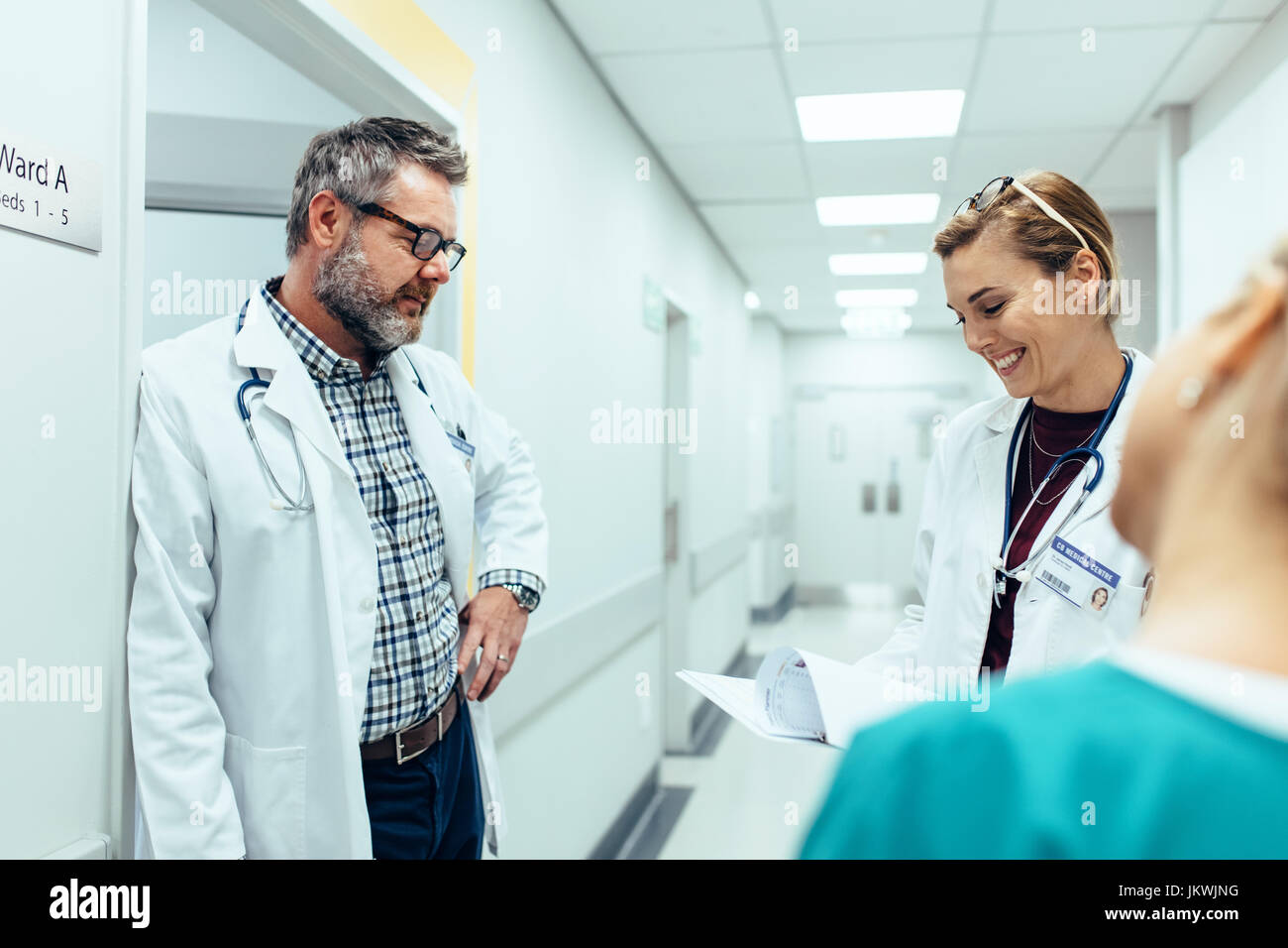 Médecin avec des collègues standing in hospital hallway. Le personnel de l'hôpital et de travail à la recherche sur les rapports médicaux. Banque D'Images