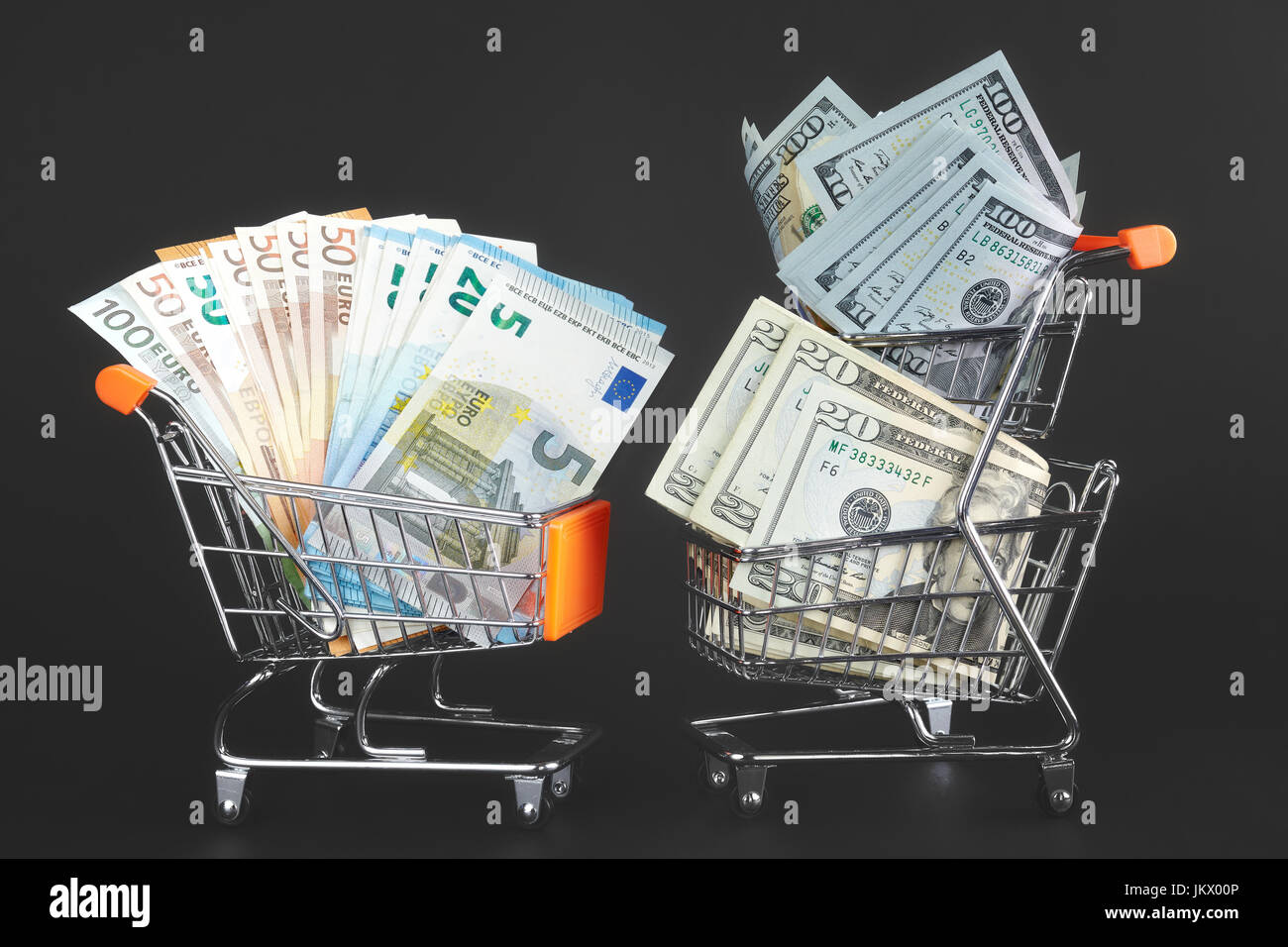 Deux chariots de magasinage avec un rival de devises, rempli de billets de dollars US et un autre avec des billets en euros, image conceptuelle. Banque D'Images
