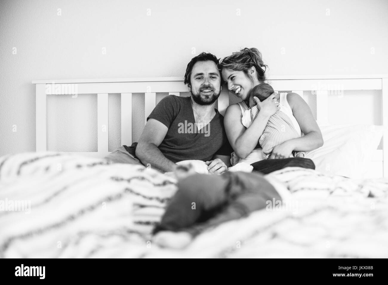 Les jeunes parents dans le lit avec leurs petits enfants Banque D'Images