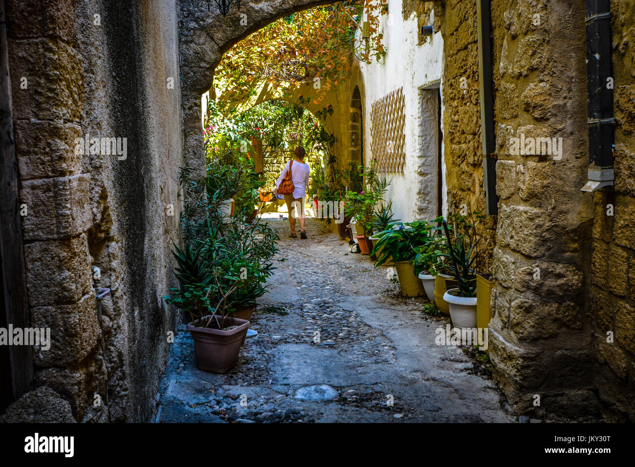 Seule femelle traveler walking cours des deux chats errants dans une ruelle de la ville méditerranéenne de Rhodes, Grèce Banque D'Images