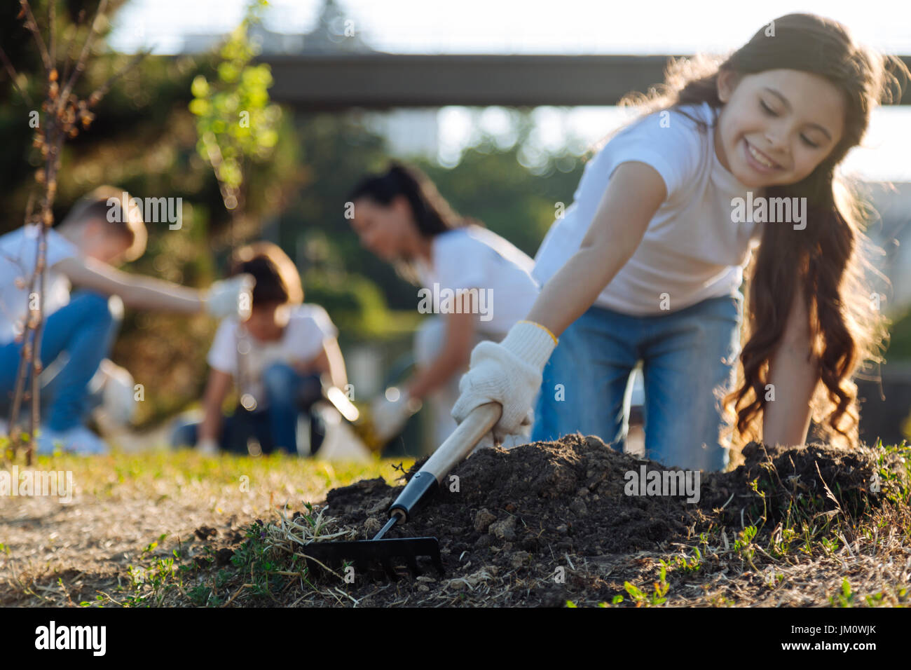 Une brunette aux cheveux longs debout sur les genoux tout en faisant du jardinage Banque D'Images