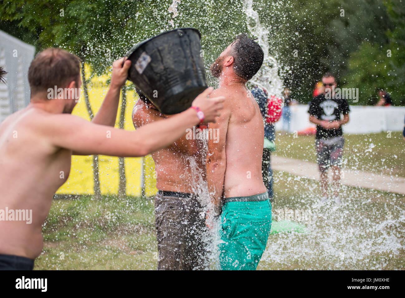 BONTIDA POUR, Roumanie - 16 juillet 2017 : mec drôle spours l'eau d'un seau sur son ami à la tête du Festival Château électrique Banque D'Images