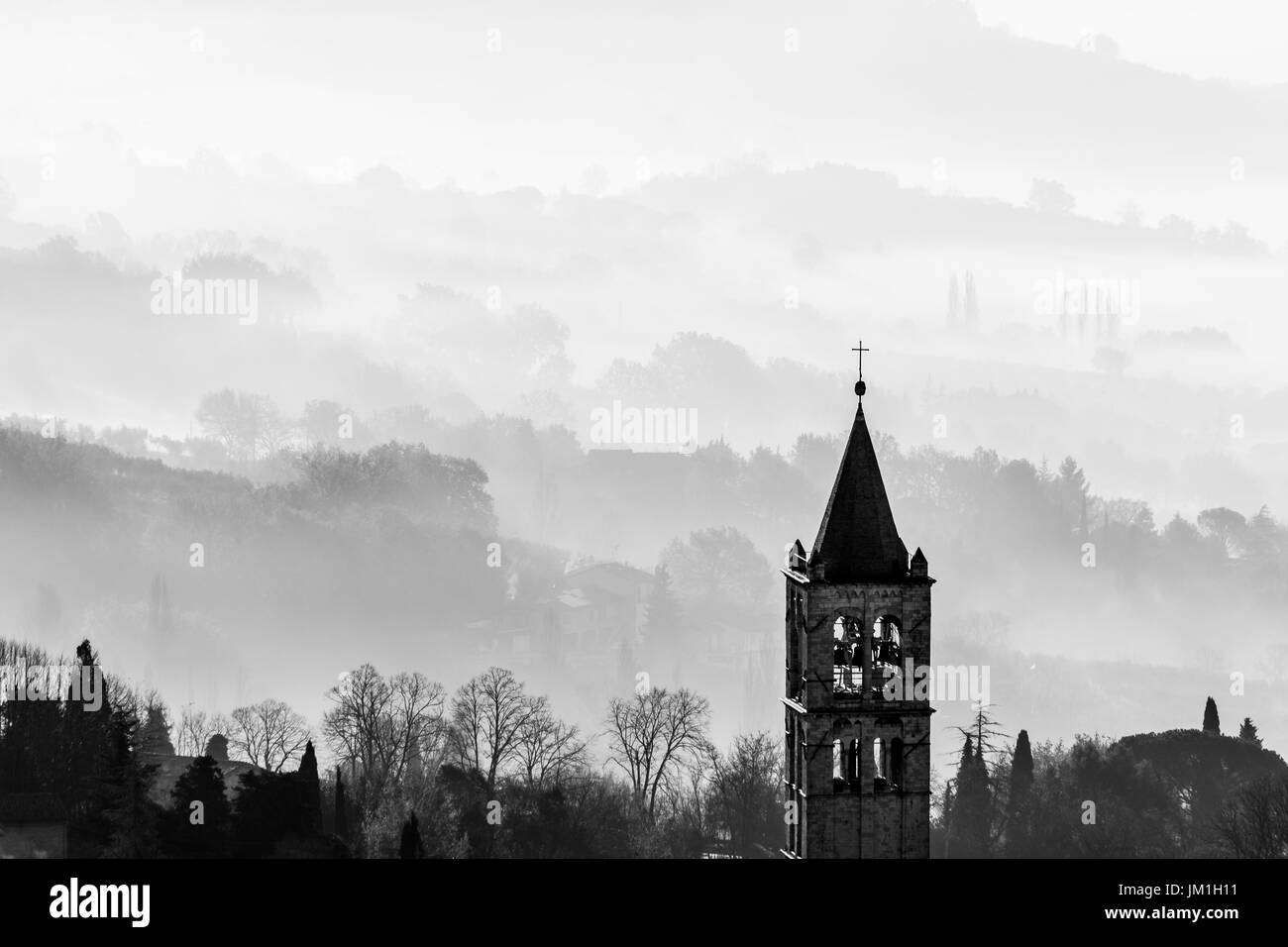 Un zoom avant vue sur le clocher de l'église de sainte Claire d'Assise (Italie) avec du brouillard à l'arrière-plan Banque D'Images
