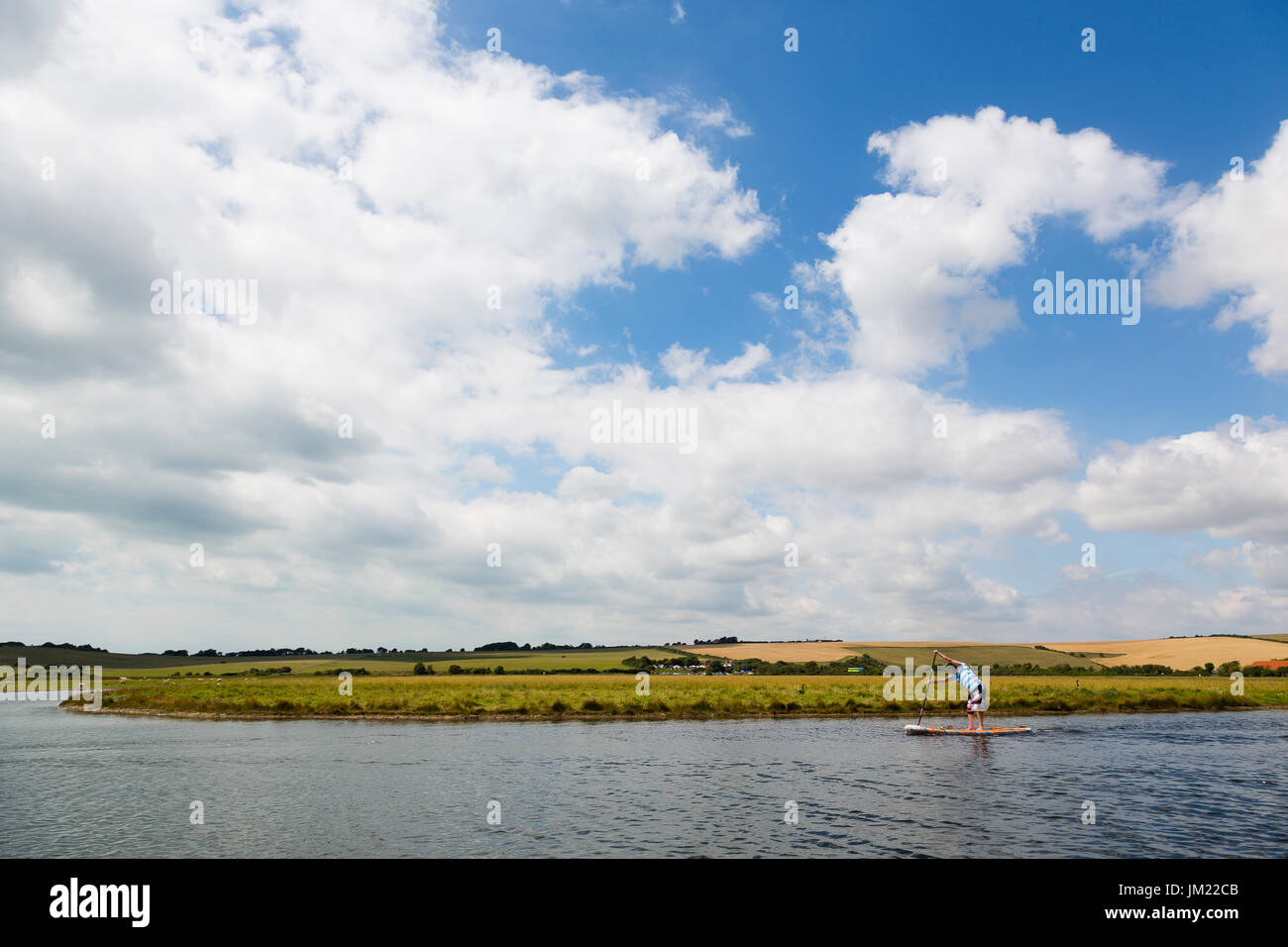 Sept Sœurs, Sussex, UK. Le 25 juillet, 2017. Un paddleboarder tête en bas la rivière Cuckmere Cuckmere Haven vers sous un ciel bleu lumineux. Crédit : Dave Stevenson/Alamy Live News Banque D'Images