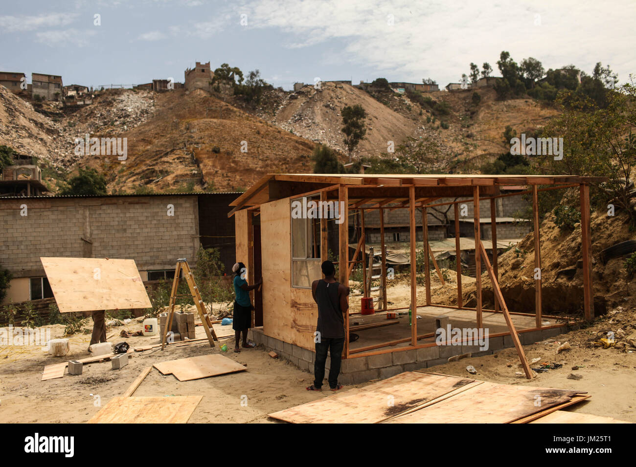 20 juillet 2017 - Tijuana, Baja California, Mexique - les migrants Haïtiens à construire un bâtiment le long d'un canal d'eau à sec situé à la périphérie de Tijuana, Baja California. Pendant la saison des pluies, le canal est contaminée par les déchets et eaux usées provenant du déversement à proximité. Le gouvernement local a refusé d'accorder des permis de construction de l'église principale abritant les migrants haïtiens dans le domaine prétendant que c'est dans une zone à risque. Cependant, le pasteur de l'église a décidé d'aller de l'avant avec la construction des maisons pour les migrants en notant que la situation est une crise humanitaire et peu à Banque D'Images