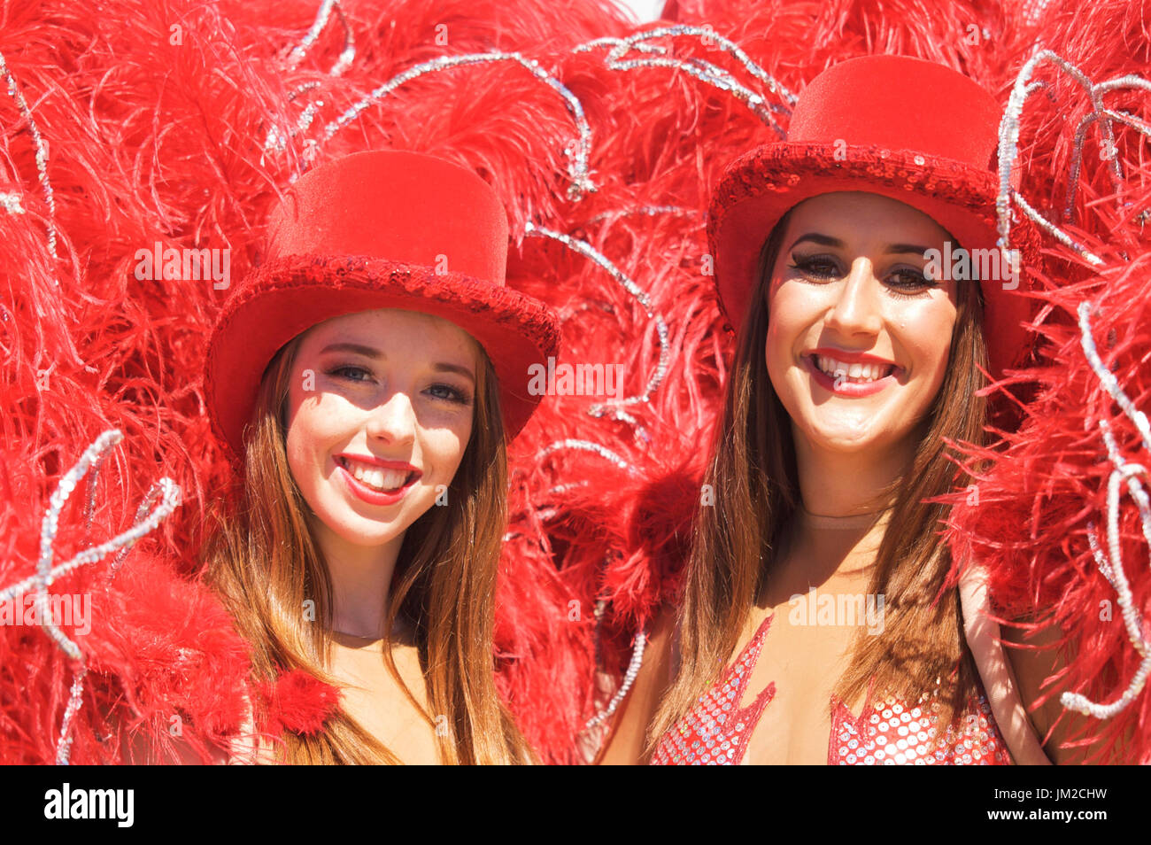 Young show in red feather costumes et chapeaux haut-de-rouge Banque D'Images
