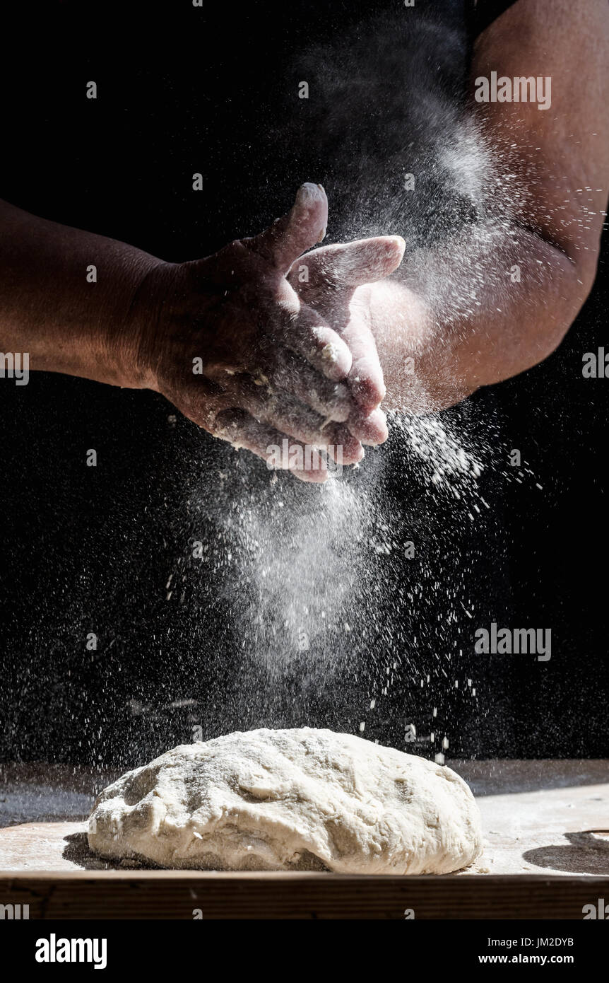 Grand-mère Noël cuisson pâtisserie pour pétrir, faire splash à partir de farine. Culture verticale, couleurs fanées avec focus sélectif sur les mains un vieux travail Banque D'Images