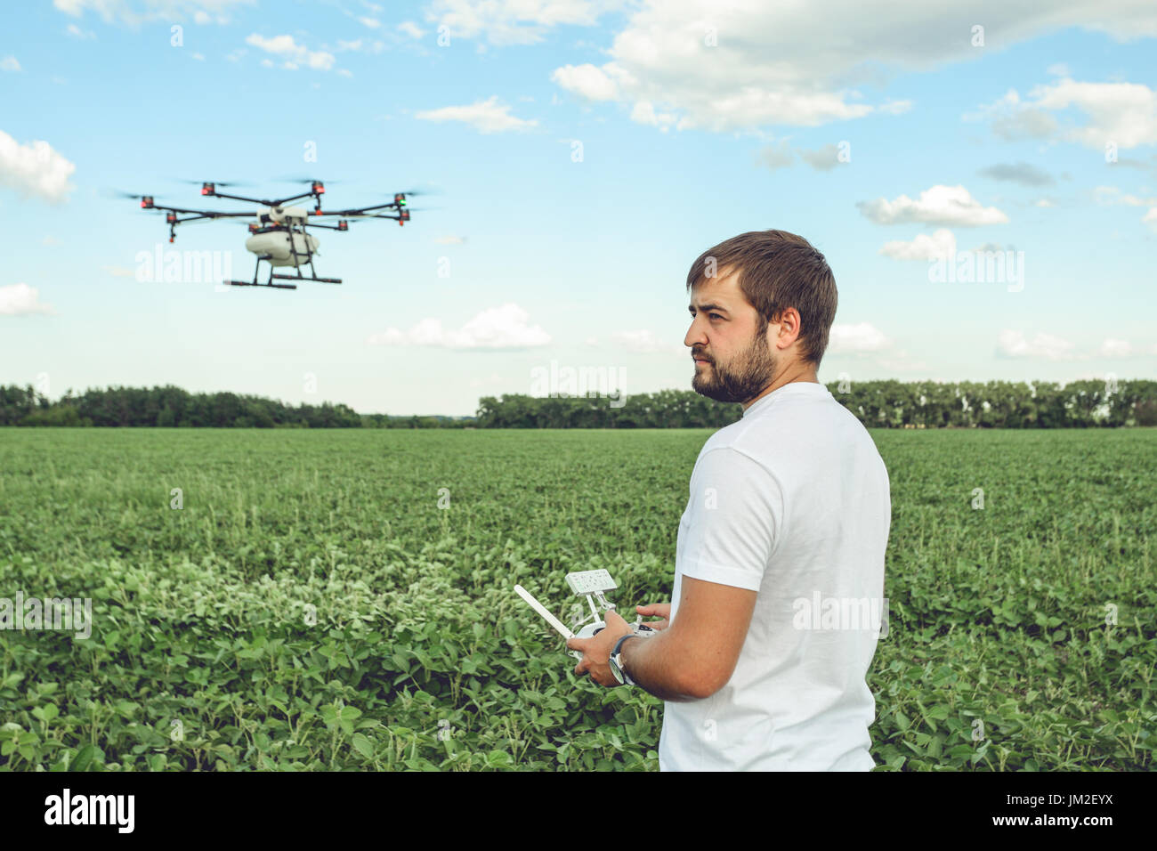 Jeune homme d'exploitation drone octocopter vol au champ vert. Banque D'Images