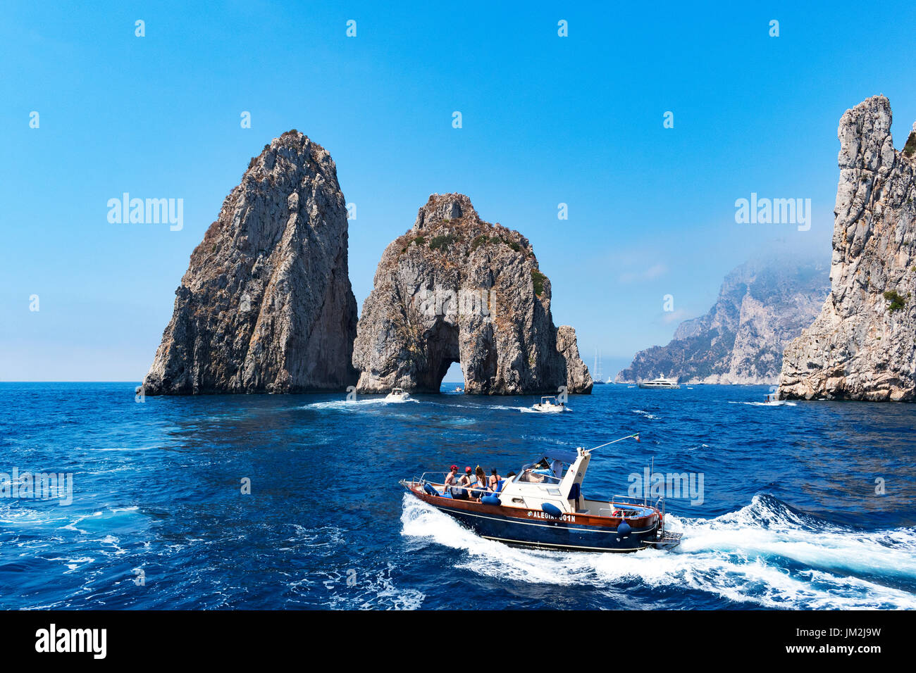 Bateaux de croisière autour de la faraglioni dans la mer tyrrhénienne, le long de la côte de l'île de Capri, Italie. Banque D'Images